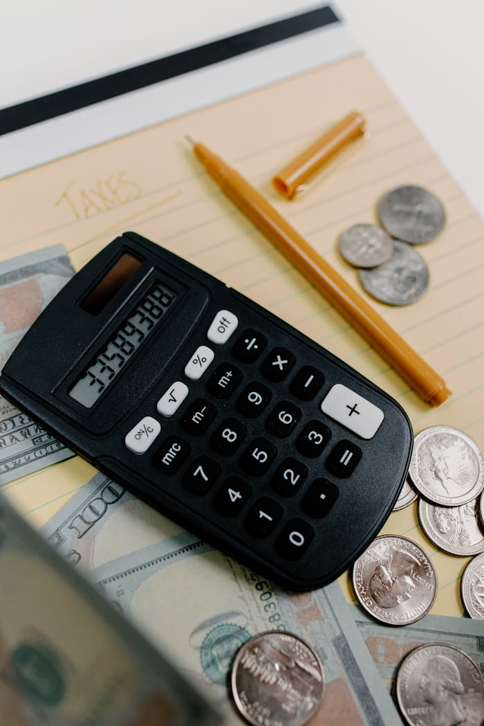 services-02 Close-up of a calculator, cash, and coins on a desk with a notepad and pen for financial planning.