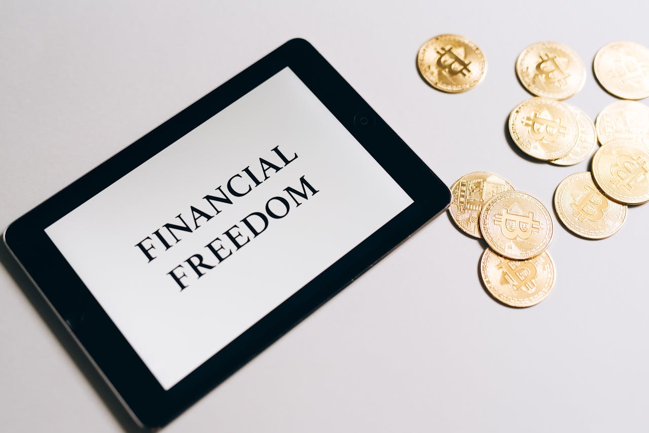 hero-img-02 Tablet showing Financial Freedom with gold bitcoins nearby, symbolizing cryptocurrency investment.